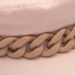 Close-up of a pink hat with a mauve chain detail on a matching pink background