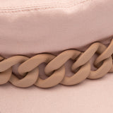 Close-up of a pink hat with a mauve chain detail on a matching pink background