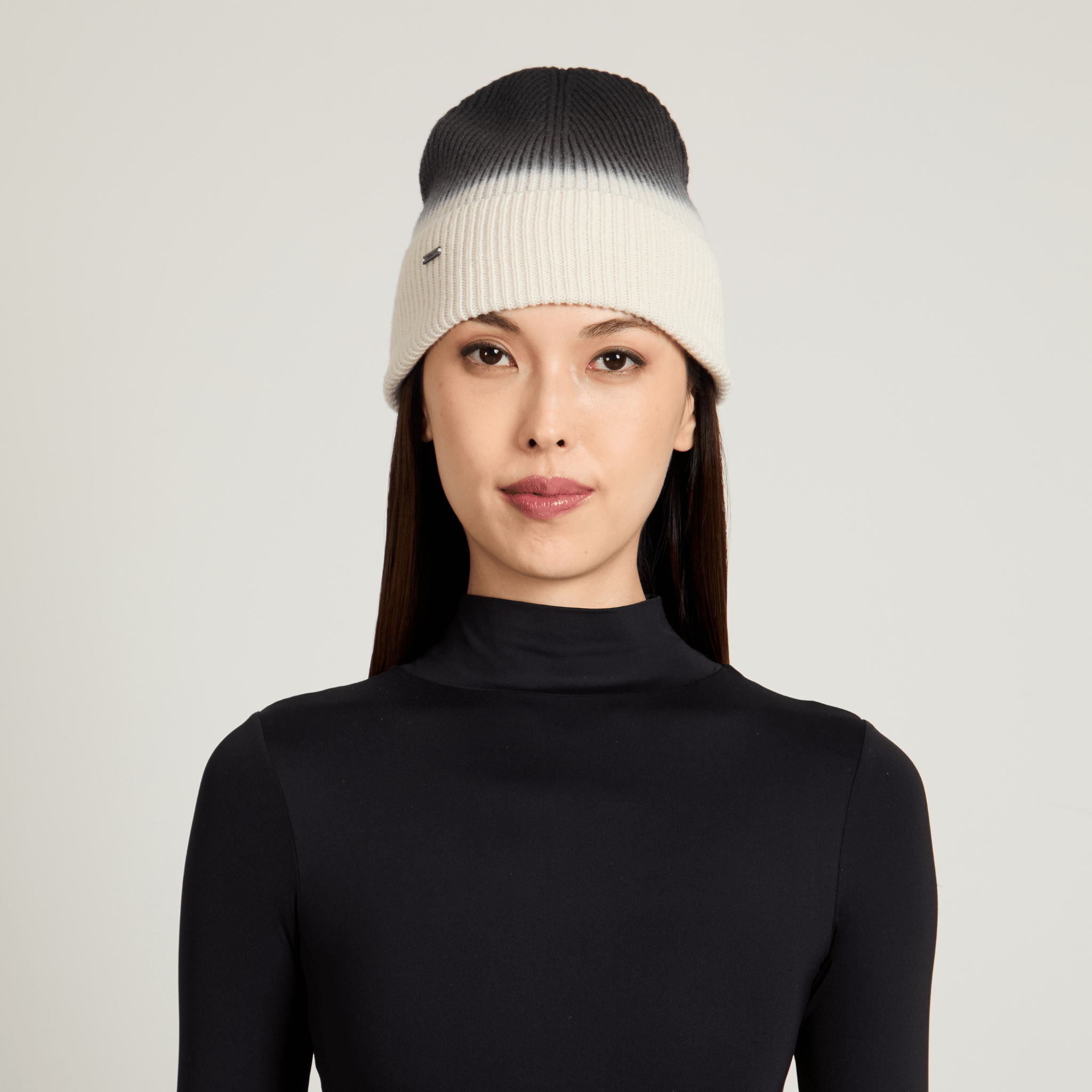 Model wearing a black and white ombre beanie on a light gray background