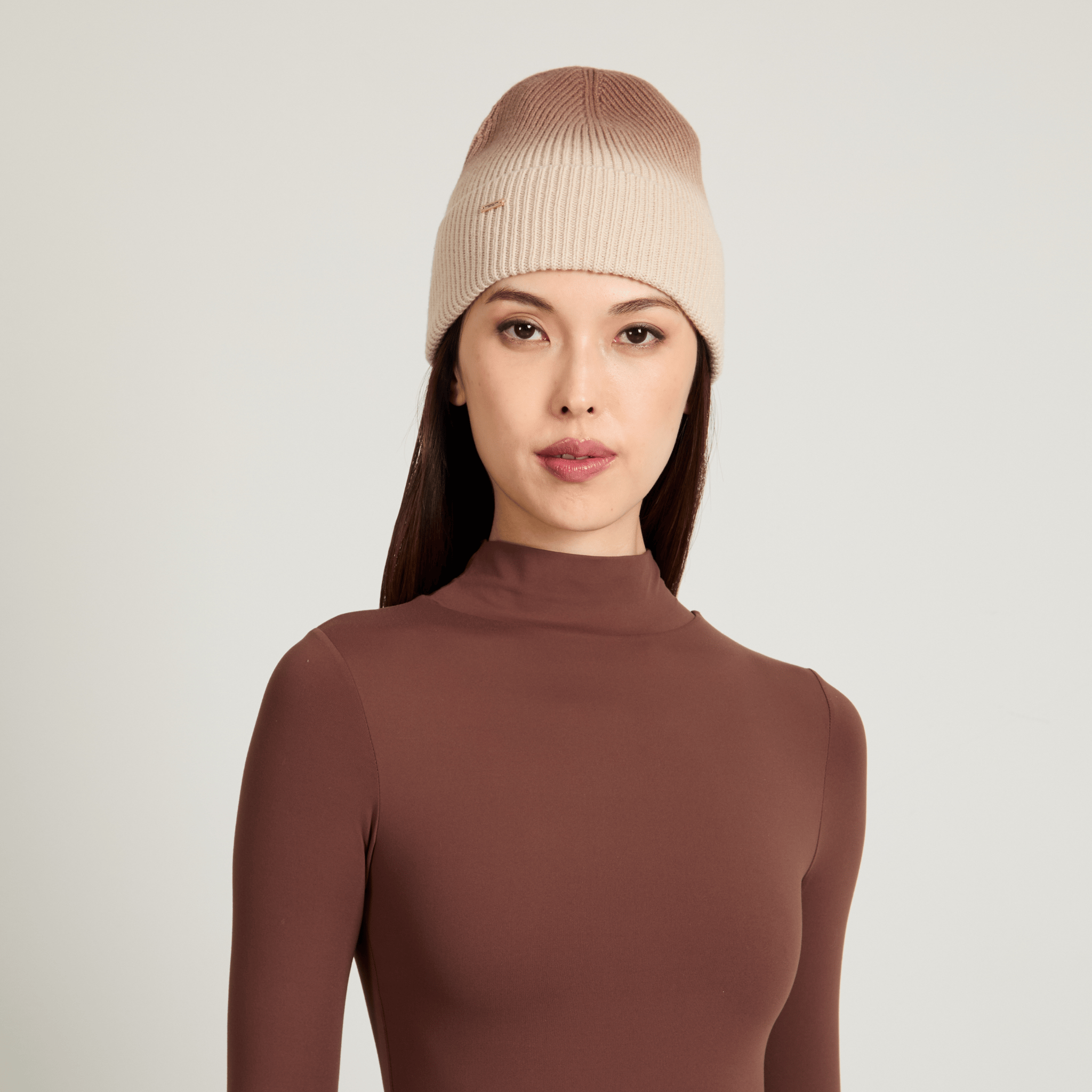 Model wearing a beige knit ombre beanie against a light gray background