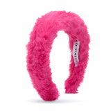 Pink fuzzy headband with a visible brand label on a white background