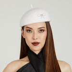 White beret with a decorative bow on model