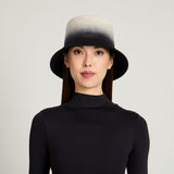 Woman wearing a black and gray gradient hat on a light gray background