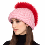 Woman wearing a pink knit beanie with a red pom-pom on a white background