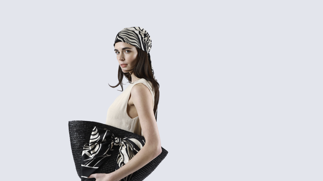 Woman holding a black handbag with zebra pattern against a light gray background