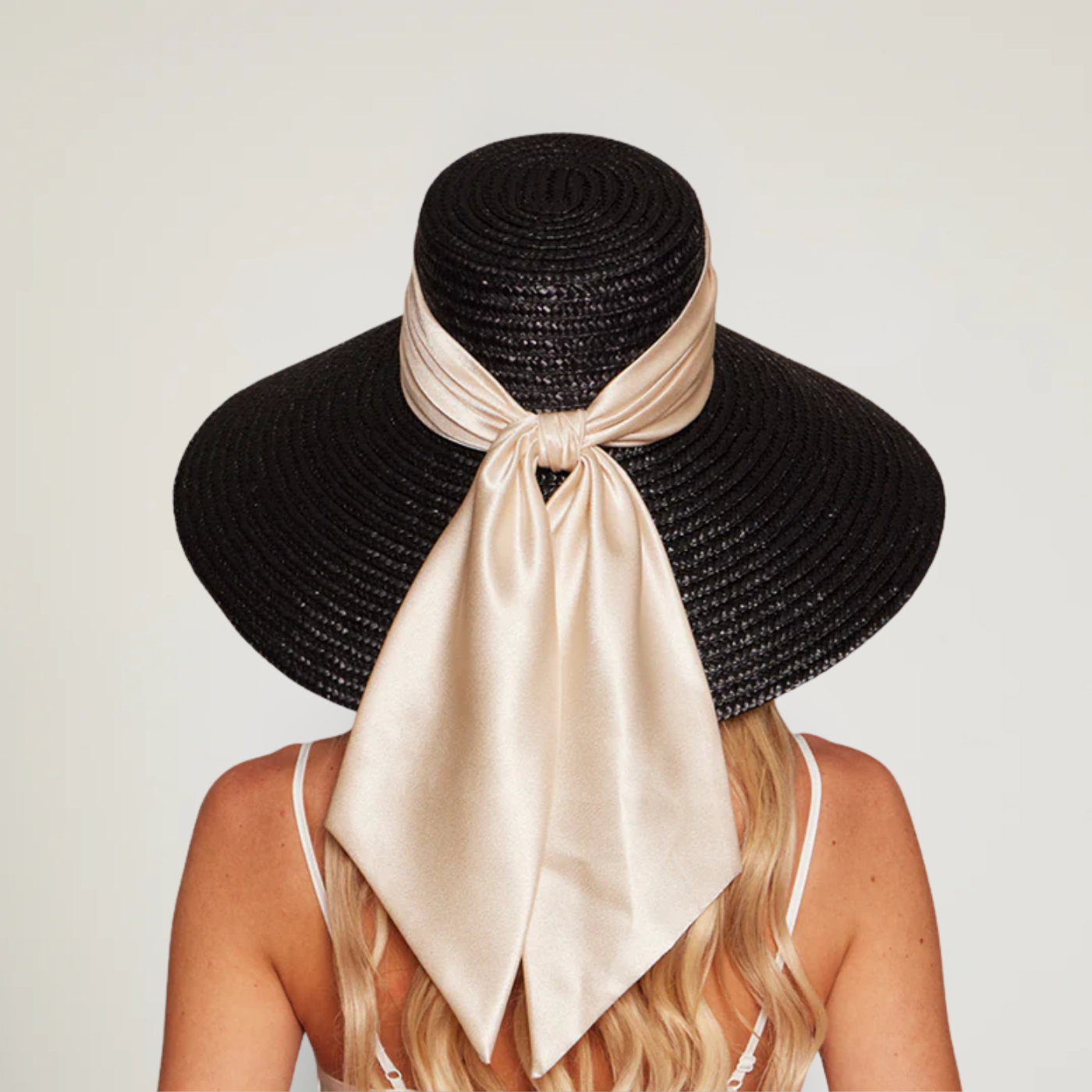 Model wearing the Mirabel wide-brim black straw sunhat with ivory satin ribbon