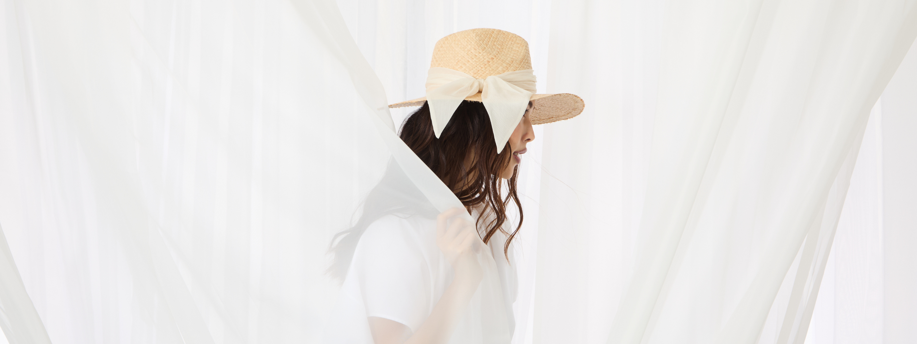 Woman wearing an Eugenia Kim straw hat with a large ivory bow, featured in the Black Friday Insider Access exclusive early access sale campaign.