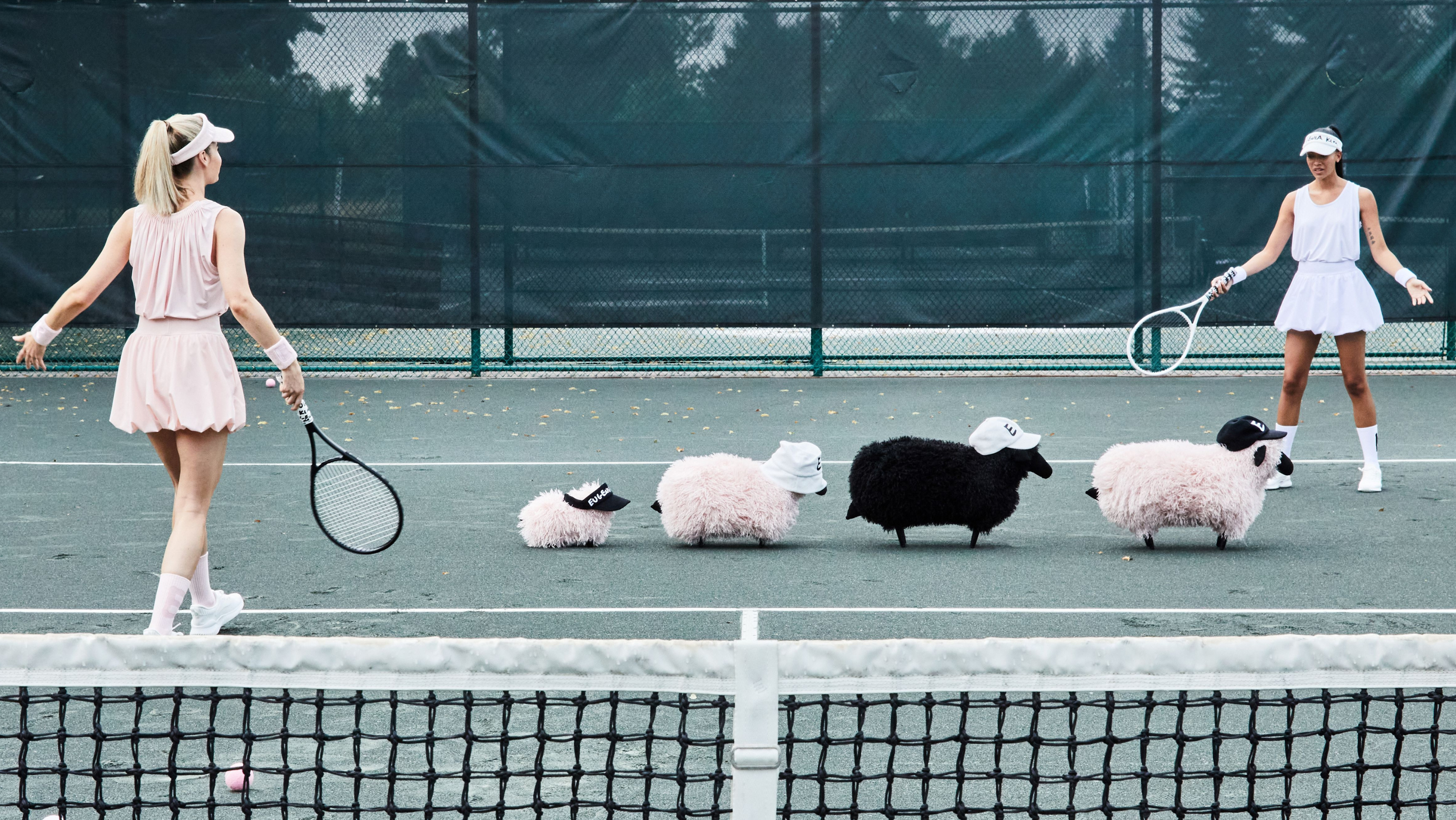 Models wearing Eugenia Kim EK LOVE tennis-inspired hats and headbands in white and neutral tones on a tennis court, featured in the 60% Off Black Friday Insider Collection.