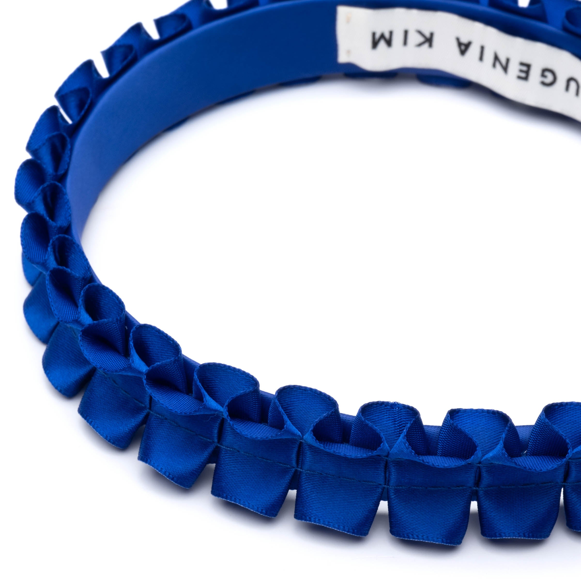 Eugenia Kim Rafaela Headband in Cobalt. A statement royal blue satin headband featuring intricate pleated ribbon design, offering a chic and modern accessory for any outfit.